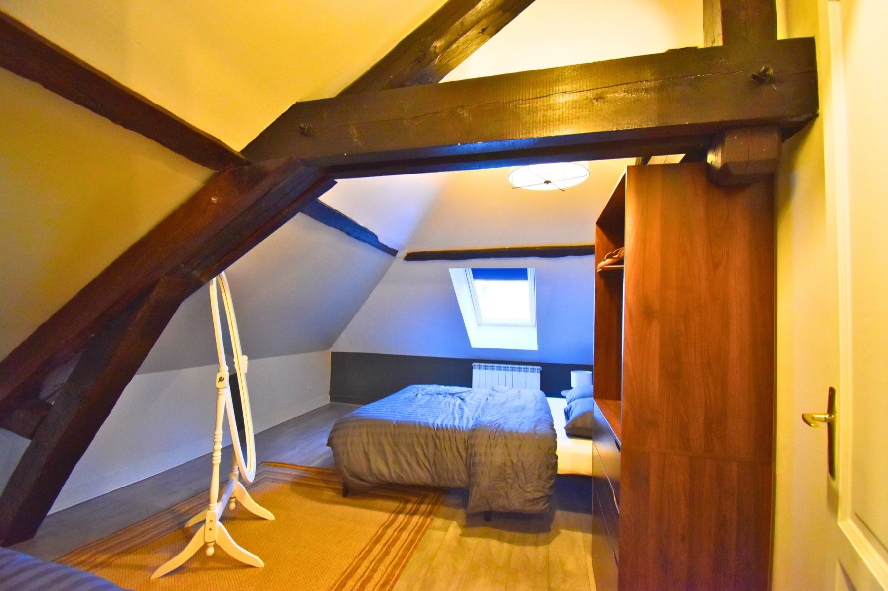 Chambre mansardée avec poutres apparentes pour héberger les invités d'un mariage au Château de Ravenel